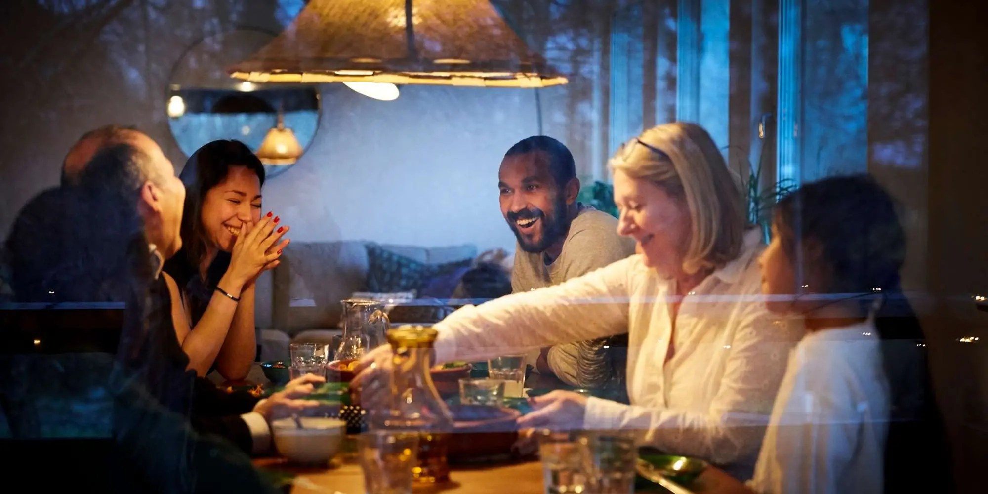 Familj och vänner sitter runt ett bord , äter och samtalar.